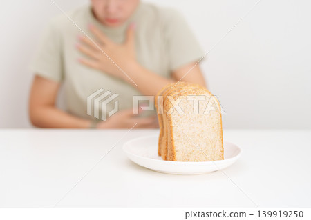Gluten intolerance, Gluten free and celiac disease or Wheat allergy. woman with wheat bread and having abdominal pain after eat gluten. stomach ache, Nausea, Bloating, Gas, Diarrhea and Skin rash 139919250
