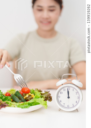 happy smiling woman with fresh organic vegetables plate and alarm clock. intermittent fasting, IF, meal time, nutrition, weight loss, clean eating, Healthy food eating, Wellness, dieting and lifestyle happy smiling woman with fresh organic vegetables plate and alarm clock. intermittent fasting, IF, meal time, nutrition, weight loss, clean eating, Healthy food eating, Wellness, dieting and lifestyle 139919262
