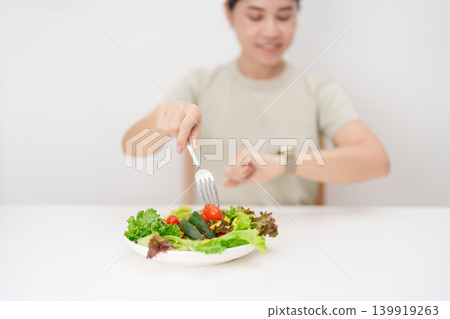 happy smiling woman with fresh organic vegetables plate and checking time. intermittent fasting, IF, nutrition control, weight loss, clean eating, Healthy food eating, Wellness, dieting and lifestyle 139919263