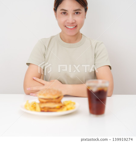 happy woman with Juicy beef burger with melted cheddar cheese, potato chips and carbonated Soft drinks. Unhealthy, High calorie, Fast food craving, Obesity, diet, weight loss, junk food and lifestyle 139919274