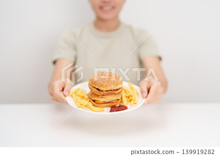 happy woman eating Juicy beef burger with melted cheddar cheese, potato chips. Unhealthy, High calorie, Fast food craving, Obesity, diet, weight loss, junk food and lifestyle 139919282