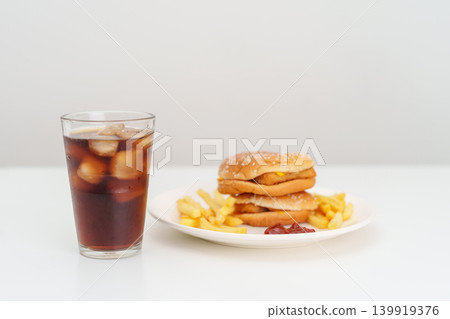 juicy beef burger with melted cheddar cheese, potato chips and carbonated Soft drinks on table. Unhealthy, High calorie, Fast food craving, Obesity, diet, weight loss, junk food and lifestyle juicy beef burger with melted cheddar cheese, potato chips and carbonated Soft drinks on table. Unhealthy, High calorie, Fast food craving, Obesity, diet, weight loss, junk food and lifestyle 139919376