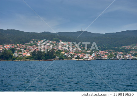 Small coastal houses integrated into the green landscape of the Vigo estuary, photographed from the sea Small coastal houses integrated into the green landscape of the Vigo estuary, photographed from the sea 139919620
