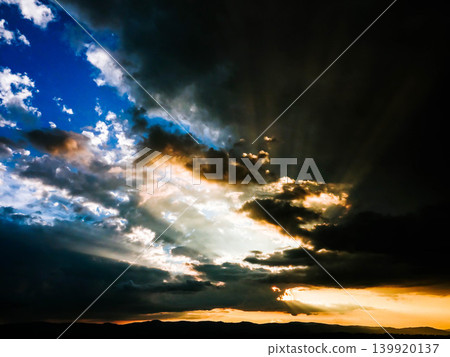A scene of rays of light shining through gaps in the clouds at sunset in Biei, Hokkaido, during the summer. A scene of rays of light shining through gaps in the clouds at sunset in Biei, Hokkaido, during the summer. 139920137