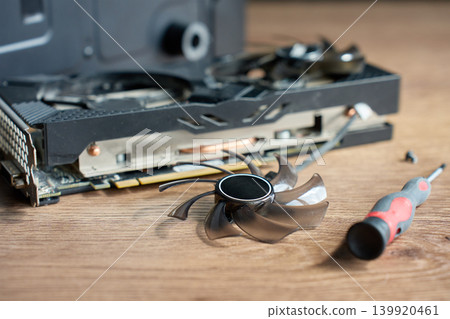 Disassembled graphics card fan with screwdriver on table 139920461