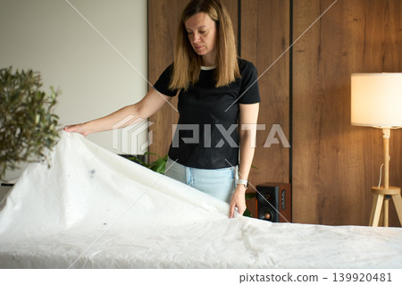 Woman preparing table with protective plastic sheet Woman preparing table with protective plastic sheet 139920481