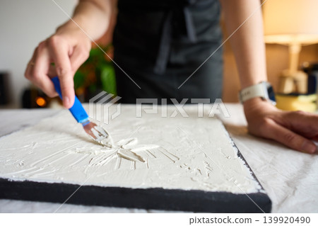 Woman making textured picture on canvas Woman making textured picture on canvas 139920490