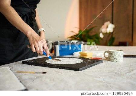 Woman making handmade wall decor on black canvas Woman making handmade wall decor on black canvas 139920494