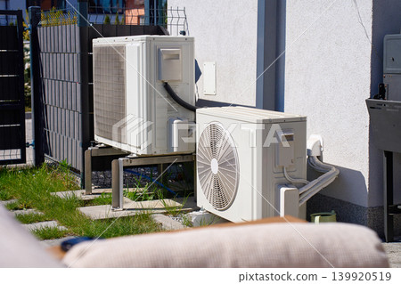 Outdoor heat pump units installed near house exterior wall Outdoor heat pump units installed near house exterior wall 139920519