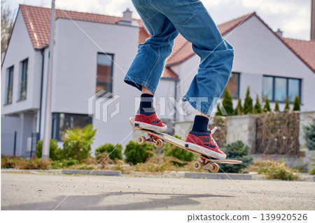 Skateboard trick on suburban street near modern house Skateboard trick on suburban street near modern house 139920526