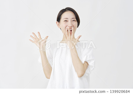一位中年婦女在白色背景前露出驚訝的笑容。 139920684