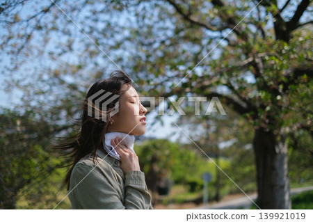 A woman wiping sweat from her face with a handkerchief in the summer heat. A woman wiping sweat from her face with a handkerchief in the summer heat. 139921019
