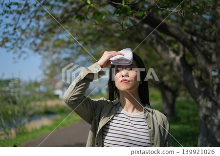 夏日炎炎,一位女士用手帕擦去額頭上的汗。 夏日炎炎,一位女士用手帕擦去額頭上的汗。 139921026