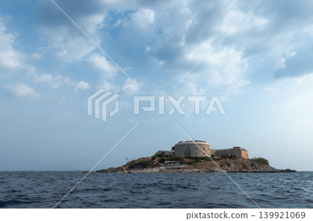 An ancient fortress is perched on a small island surrounded by the calm sea An ancient fortress is perched on a small island surrounded by the calm sea 139921069