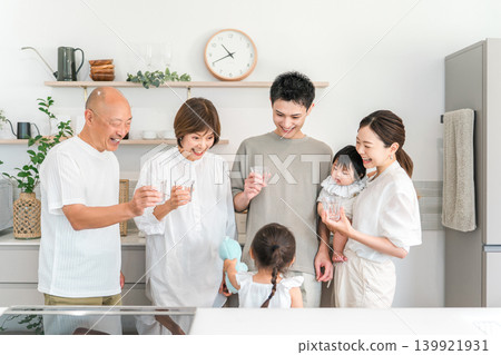 A three-generation family drinking water in their home kitchen. 139921931
