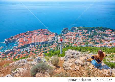 Girl enjoys view of old town (medieval Ragusa) and Dalmatian Coast of Adriatic Sea in Dubrovnik Girl enjoys view of old town (medieval Ragusa) and Dalmatian Coast of Adriatic Sea in Dubrovnik 139922036