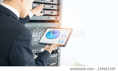 A male engineer inspecting a server. A male engineer inspecting a server. 139922320
