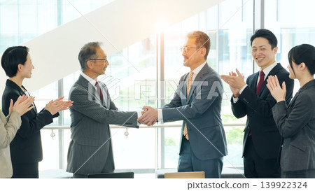 A group of business professionals of various ages, both male and female, shaking hands. 139922324