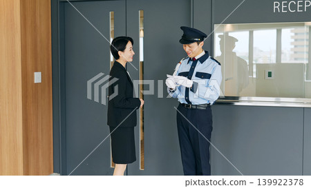 A male security guard checks the ID of a female staff member. A male security guard checks the ID of a female staff member. 139922378