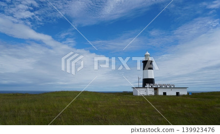 A grassland under a blue sky and a lighthouse (Notoro Cape Lighthouse, Hokkaido) - empty space on the left. A grassland under a blue sky and a lighthouse (Notoro Cape Lighthouse, Hokkaido) - empty space on the left. 139923476