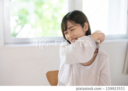 一位年輕的日本女性正在用按摩槍為自己做肩部按摩。 139923551