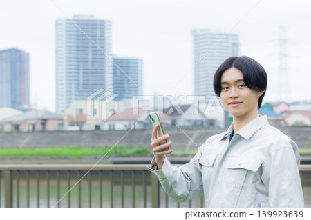 Worker looking at his smartphone Worker looking at his smartphone 139923639