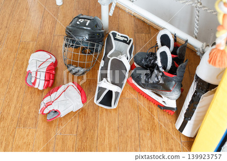 Hockey gear is arranged on a wooden floor in a training space Hockey gear is arranged on a wooden floor in a training space 139923757
