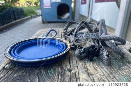 Dog walking items left on a wooden table near a trash can in an outdoor area Dog walking items left on a wooden table near a trash can in an outdoor area 139923768