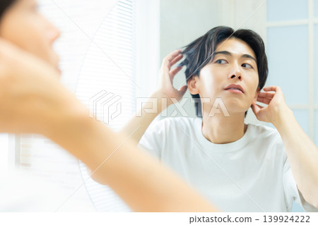man looking in the mirror in the bathroom man looking in the mirror in the bathroom 139924222