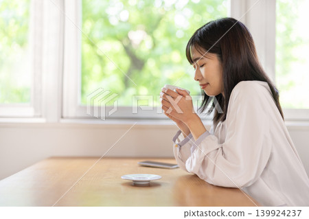 一位年輕的日本女子在靠窗的桌旁享用咖啡。 139924237