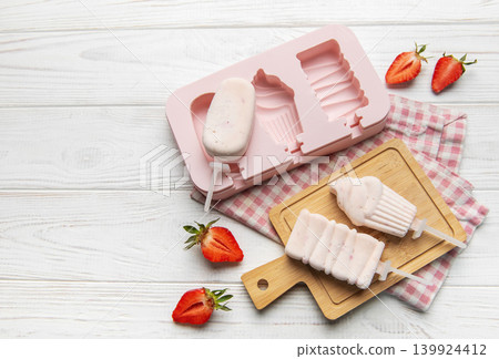 Homemade strawberry yogurt popsicles on white wooden table Homemade strawberry yogurt popsicles on white wooden table 139924412