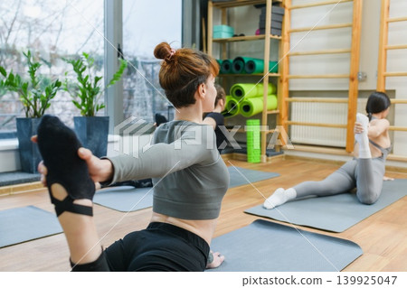 Women performing king cobra yoga pose in studio Women performing king cobra yoga pose in studio 139925047
