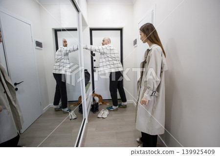 Couple interacts in hallway with mirror before leaving home for the day Couple interacts in hallway with mirror before leaving home for the day 139925409