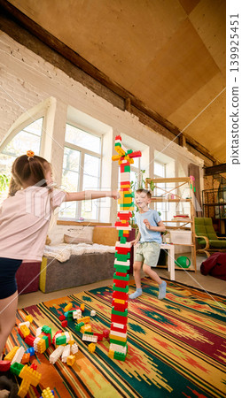 Children playing with tall block tower in colorful indoor playroom. Children playing with tall block tower in colorful indoor playroom. 139925451