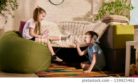 Happy children playing together near sofa in cozy creative room. Happy children playing together near sofa in cozy creative room. 139925462