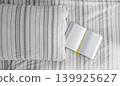 Striped cushion and open books on a grey fabric background 139925627