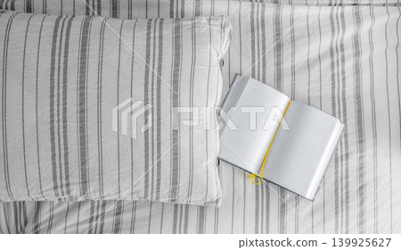 Striped cushion and open books on a grey fabric background Striped cushion and open books on a grey fabric background 139925627