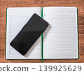 Top view of black smartphone on open blank notebook diary 139925629