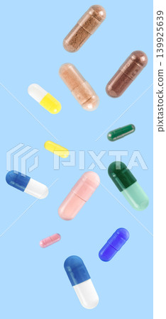 Falling white medicine pills capsule isolated on blue background Falling white medicine pills capsule isolated on blue background 139925639