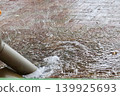 Rainwater overflowing from gutters in a parking lot during a torrential downpour. 139925693
