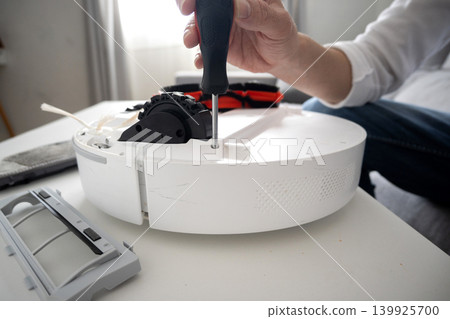 Man cleaning and maintaining robotic vacuum cleaner at home 139925700