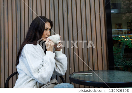 Pretty woman drinking coffee in city street cafe outdoors 139926598