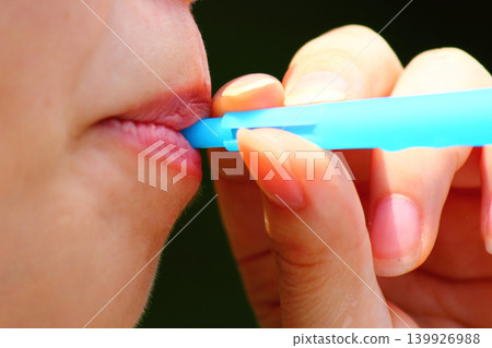 A woman's mouth as she blows soap bubbles. A woman's mouth as she blows soap bubbles. 139926988