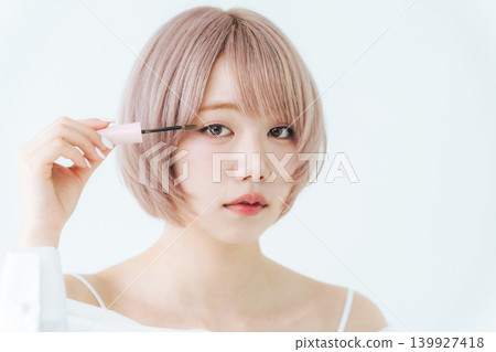 一位留著淺色短波波頭的女士正在塗睫毛膏。 139927418