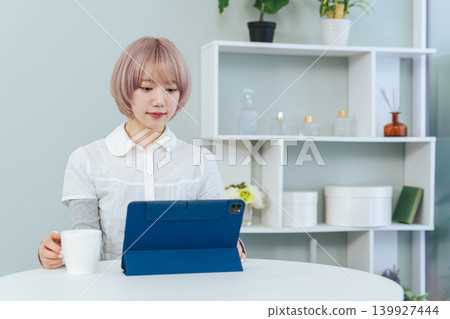 一位淺色頭髮的女子正在看著平板電腦。 一位淺色頭髮的女子正在看著平板電腦。 139927444