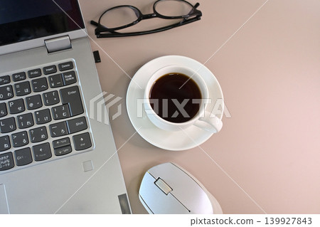 A landscape view of someone working from home, with a laptop, coffee, and glasses, seen from directly above. A landscape view of someone working from home, with a laptop, coffee, and glasses, seen from directly above. 139927843