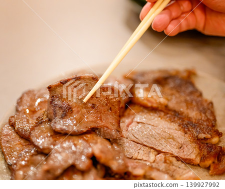 Picking up grilled meat with chopsticks Picking up grilled meat with chopsticks 139927992