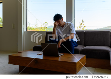 A man struggling with his laptop on the sofa. A man struggling with his laptop on the sofa. 139928057