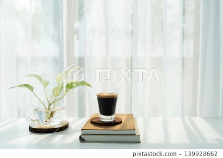 Coffee glass cup on stack of notebooks with pothos plant Coffee glass cup on stack of notebooks with pothos plant 139928662