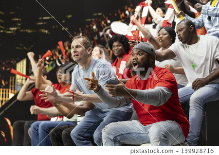 Diverse football fans following live score for betting odds on phone, cheering and watching intense soccer match at stadium. Supporters use mobile betting app for high risk wager, sports betting. Diverse football fans following live score for betting odds on phone, cheering and watching intense soccer match at stadium. Supporters use mobile betting app for high risk wager, sports betting. 139928716